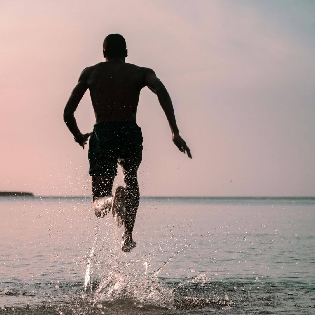 A man running into the sea at dusk